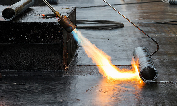 a gas torch heating a metal pipe with flame while performing industrial work related to five fabrication processes