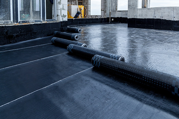 construction site showing black waterproofing rolls on a concrete floor seven layers of protection visible