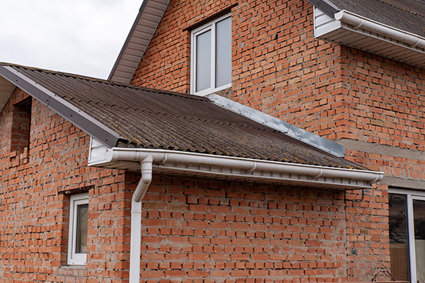 brick house exterior with slanted roof and guttering showing construction quality and maintenance important for durability and longevity 7 styles of roofing options