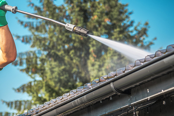 man using a pressure washer to clean a roof with water spray effective cleaning solution for home maintenance 5 unique benefits