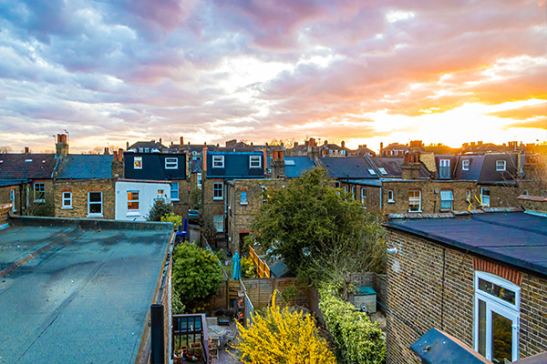 rooftops of houses at sunset with colorful clouds and greenery in view perfect for 4 urban settings