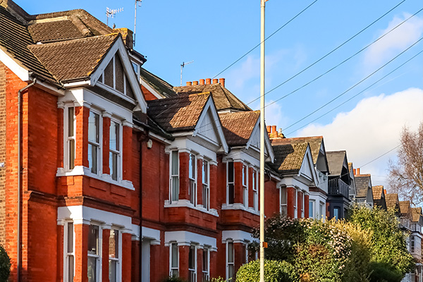 row of red brick Victorian houses with white trim and blue sky in the background representing residential architecture and urban living
