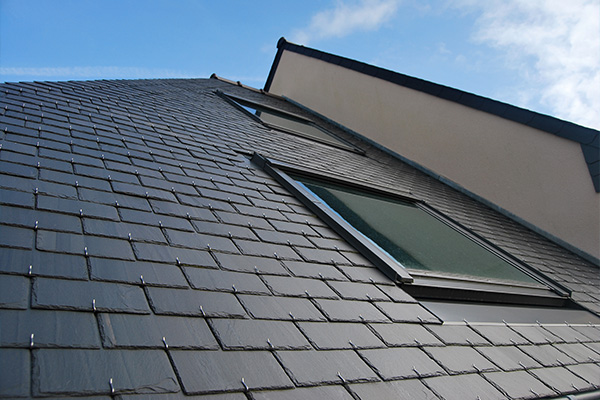 slate roof with windows under a blue sky in residential building showing modern design and two sloped surfaces