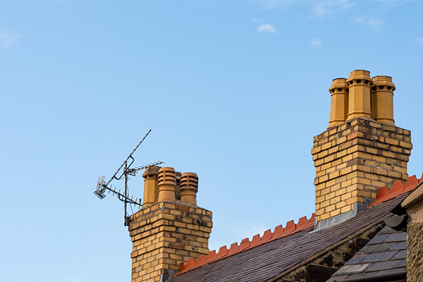 multiple brick chimneys on a rooftop under clear blue sky with television antenna displaying number 11