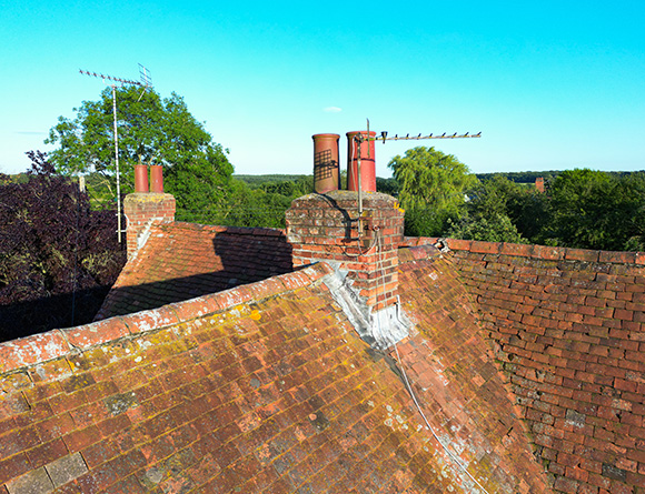 view of a roof with multiple chimneys satellite dishes and green trees in the background showcasing a clear blue sky and the beauty of residential architecture 8 features roof design