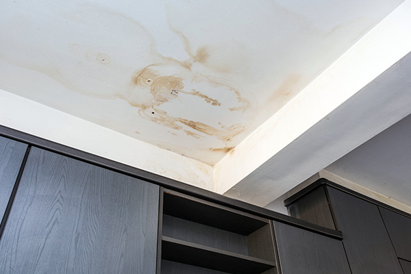 water damage on ceiling near cabinets showing brown stains and discoloration in a residential space indicating possible leaks and maintenance issues 2 fix repair