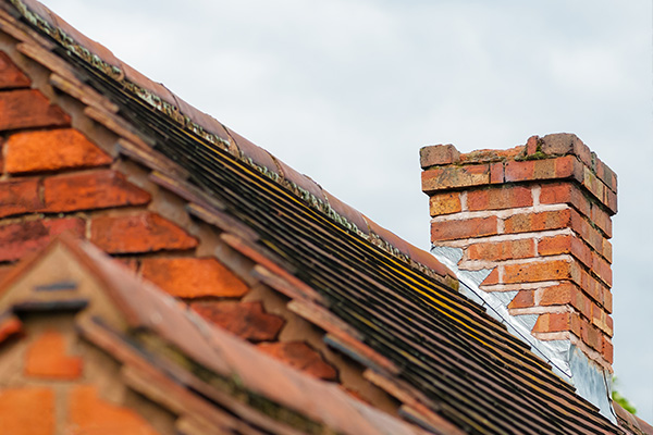 roofline with brick chimney and six sloped tiles