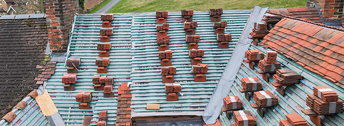overhead view of red and green tiled roofs with stacks of bricks for roofing repair and maintenance of structures
