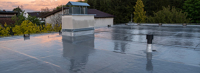 flat roof with a silver finish showing a chimney and ventilation system against a colorful sunset sky suitable for modern buildings eight roofing options available