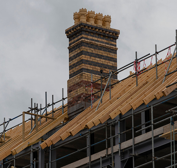 newly constructed roof featuring a prominent ornate chimney detailed with bricks under cloudy skies construction project two architectural elements