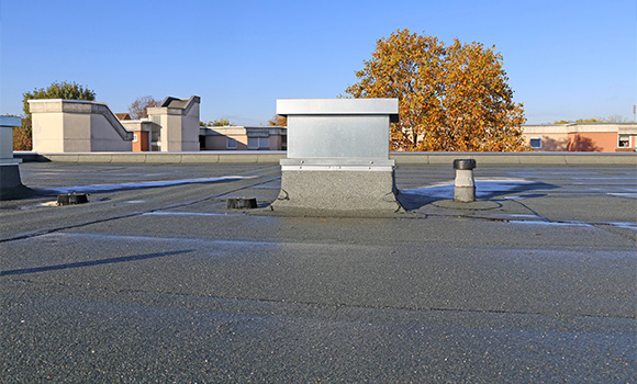 rooftop view featuring ventilation equipment and a tree in the background showcasing weather conditions and rooftop maintenance options for commercial buildings