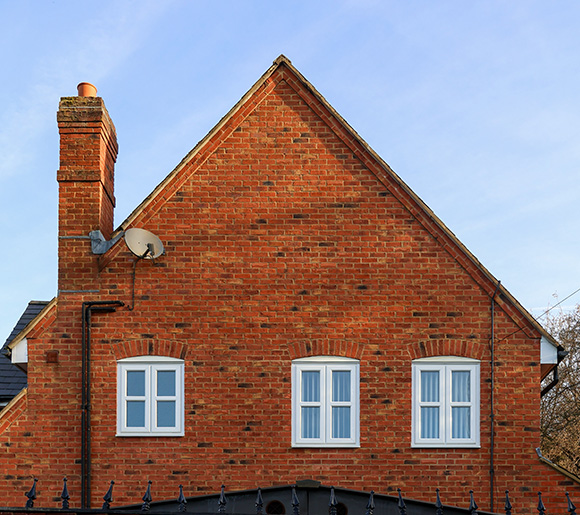 brick house exterior with six windows and a chimney