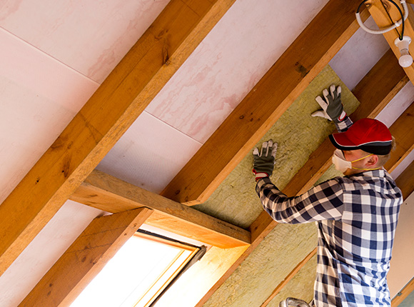 man installing insulation in attic wearing gloves and mask working on home improvement project with wooden beams and skylight six insulation tips for best results