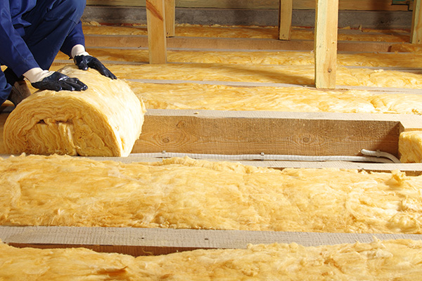 person placing insulation material in attic space to improve energy efficiency and comfort