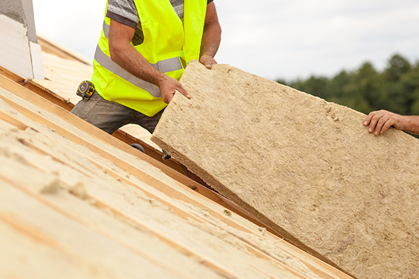 worker wearing safety vest handling insulation panel on roof 7 insulation tips for roofing