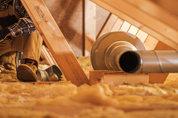 person working in an attic on insulation with ventilation duct visible promoting efficient air flow and climate control in home systems