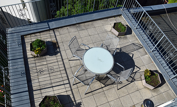 rooftop terrace with a round glass table surrounded by six chairs and potted plants ideal for outdoor relaxation and gatherings in a modern setting