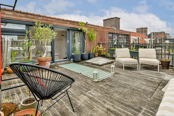 a cozy rooftop terrace featuring potted plants comfortable chairs and decorative lanterns perfect for outdoor living and relaxation