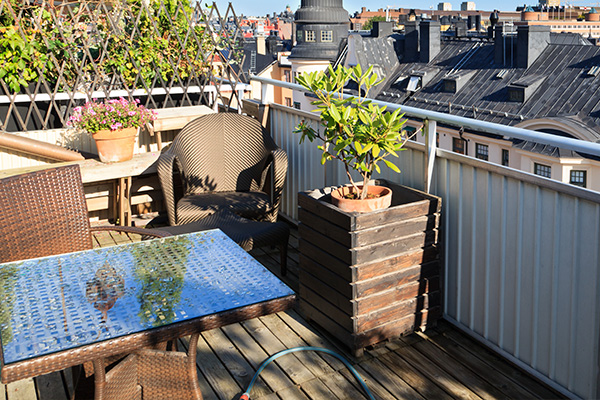 a cozy balcony with a glass table and wicker chairs overlooking rooftops and greenery in the background featuring a potted plant creating a serene outdoor space ideal for relaxing moments perfect for seven friends