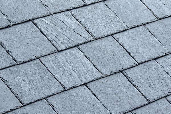detailed view of slate roofing tiles with varying textures and shades of gray showcasing two layers of durable material