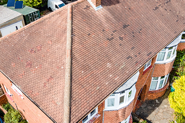 aerial view of a residential roof with brown shingles showing wear and dirt typical of four seasons maintenance needed
