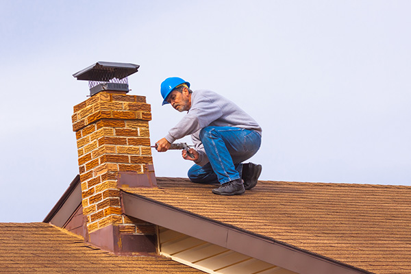 man working on a chimney on a roof wearing a safety helmet engaged in home maintenance tasks for improved roofing and chimney safety