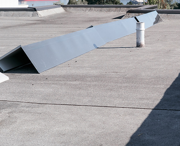Gray metal sheets on a flat roof with a ventilation pipe showcasing elements of industrial construction and maintenance featuring the number 7 prominently in design.