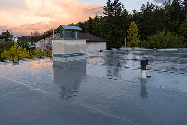 flat roof with chimney and ventilation pipes against a colorful sunset five roofing materials and techniques