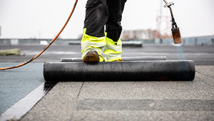 A man rolling out rubber roofing